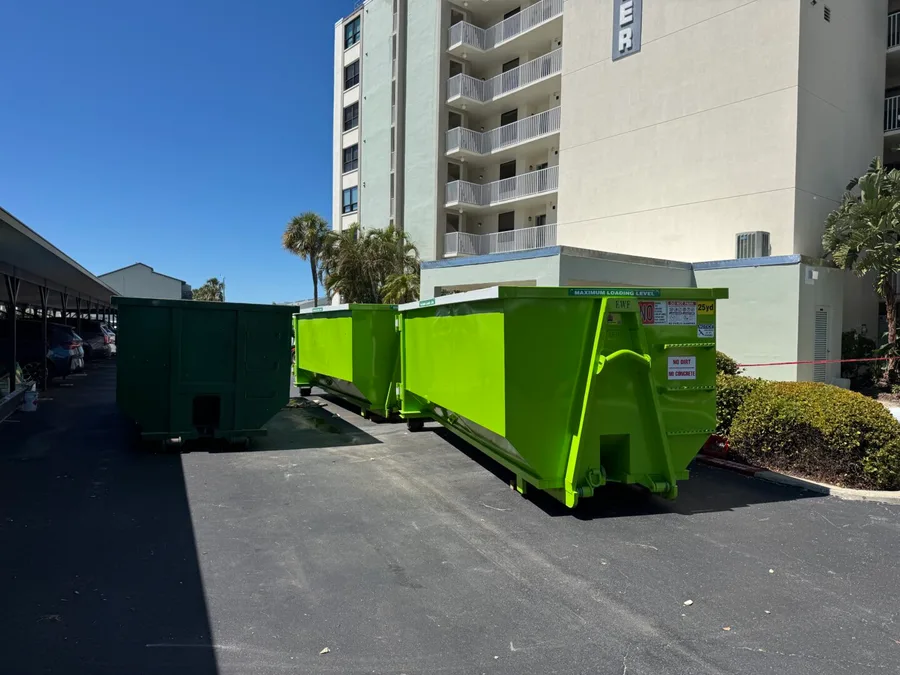 Construction crew loading demolition debris into a MAXCO dumpster